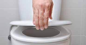 mão levantando tampa de assento de vaso sanitário