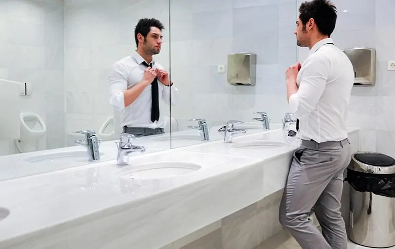 Você sabe quais produtos ajudam a implantar tecnologia no banheiro? Leia esse artigo para descobrir! Homem usando o banheiro comercial pensando em implantar tecnologia no banheiro